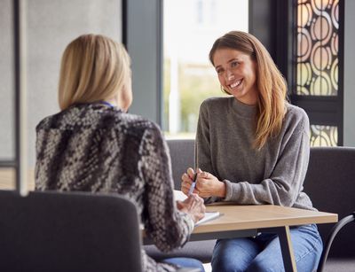 Zwei Frauen sitzen an einem Tisch und unterhalten sich.